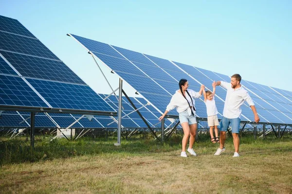 stock image Young family of three is crouching near photovoltaic solar panel, little boy and parents. modern family concept. The concept of green energy.