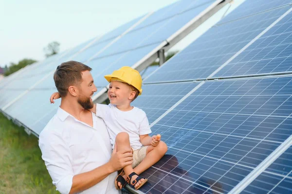 Man showing little child the solar panels during sunny day. Father presenting to his kid modern energy resource. Little steps to alternative energy