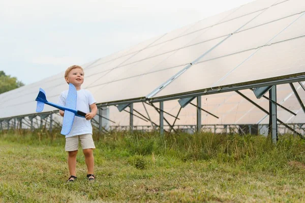 stock image Little happy boy playing with toy airplane near solar panels