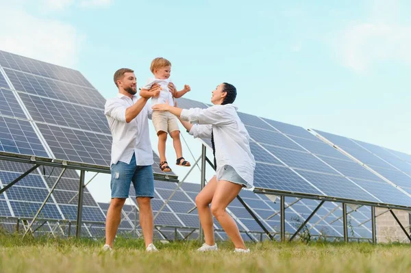 Young family of three is crouching near photovoltaic solar panel, little boy and parents. modern family concept. The concept of green energy.