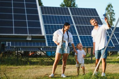 Güneş panelleri yakınında mutlu bir aile. Alternatif enerji kaynağı.