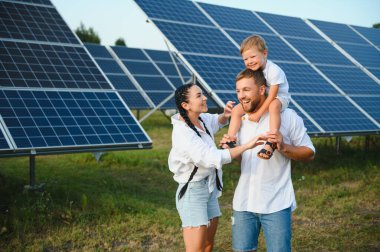 Güneş panelleri yakınında mutlu bir aile. Alternatif enerji kaynağı.