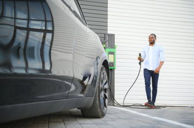 Adam şarj istasyonunda elektrikli arabasını şarj ediyor..