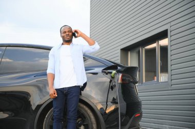 Afrikalı Amerikalı adam elektrikli arabasını şarj ediyor.