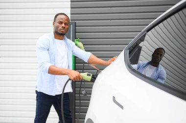 Otoparktaki ofisin dışında elektrikli araba fişi takan adam....