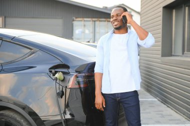 Afrikalı Amerikalı adam elektrikli arabasını şarj ediyor.