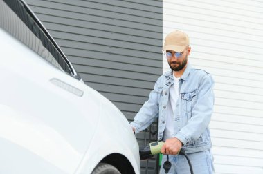 Dışarıdaki otoparkta elektrikli araba için elektrik kablosu. Ve arabayı alışveriş merkezinin yanındaki park yerindeki şarj istasyonuna bağlayacak.