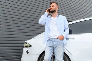 Mutlu adam akıllı telefon kullanıyor ve aracı şarj ediyor..