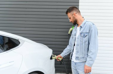Dışarıdaki otoparkta elektrikli araba için elektrik kablosu. Ve arabayı alışveriş merkezinin yanındaki park yerindeki şarj istasyonuna bağlayacak.
