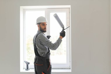 Silikon tabanca ile yapıştırıcı uygulayarak genç bir erkek işçi yan görünüm.