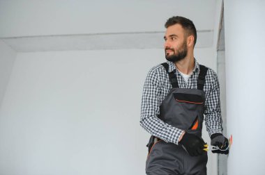 Elektrik İmalathanesi, prizler ve şalter kurulumu. Elektrikçi aletli profesyonel bir işçi. Tamir alanının arka planına karşı.