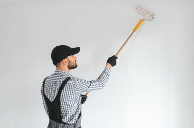 Duvarları boyayan genç bir işçi.