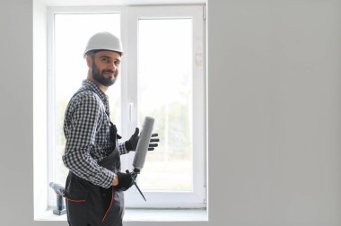 Silikon tabanca ile yapıştırıcı uygulayarak genç bir erkek işçi yan görünüm.