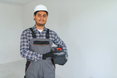 meslek, inşaat ve bina - mutlu gülümseyen Hintli işçi veya miğfer gri arka plan üzerinde inşaatçı