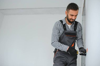 Ciddi erkek elektrikçi daireye priz yerleştiriyor ve tornavida kullanıyor..