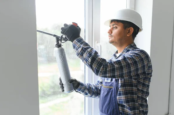 屋内窓の修理のためのシリコーン管を使用してインドの労働者 — ストック写真