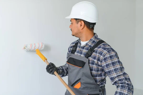 インドのアパートの修理労働者はローラーが付いている白い壁を塗ります — ストック写真