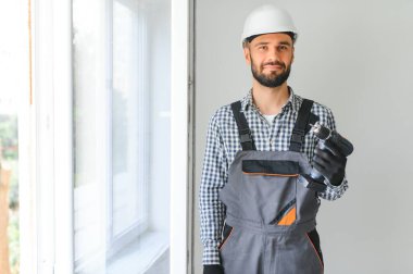 Evdeki oturma odasına plastik pencereler monte eden ya da ayarlayan işçi.