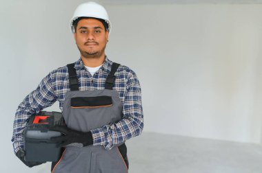 meslek, inşaat ve bina - mutlu gülümseyen Hintli işçi veya miğfer gri arka plan üzerinde inşaatçı