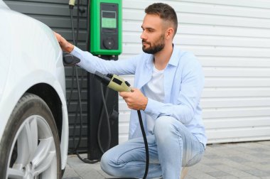 Dışarıdaki otoparkta elektrikli araba için elektrik kablosu. Ve arabayı alışveriş merkezinin yanındaki park yerindeki şarj istasyonuna bağlayacak.