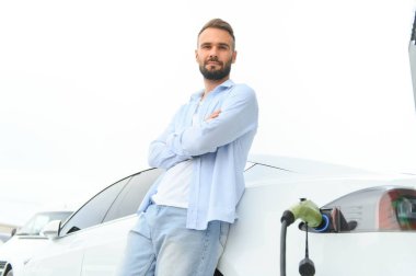 Kalkıp şarjın bitmesini bekliyorlar. Genç şık adam, gündüz vakti elektrikli arabayla geziyor..