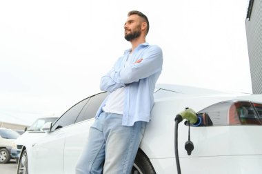 Elektrikli arabasının yanında duran adam..