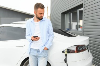 Mutlu adam akıllı telefon kullanıyor ve aracı şarj ediyor..