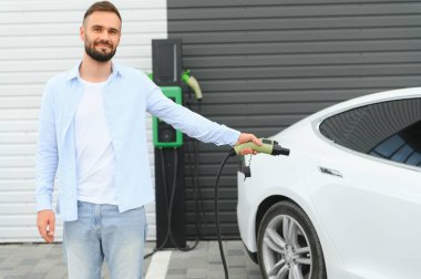 Dışarıdaki otoparkta elektrikli araba için elektrik kablosu. Ve arabayı alışveriş merkezinin yanındaki park yerindeki şarj istasyonuna bağlayacak.