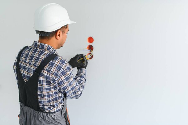 an Indian electrician installs an outlet in a new building.