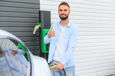 Dışarıdaki otoparkta elektrikli araba için elektrik kablosu. Ve arabayı alışveriş merkezinin yanındaki park yerindeki şarj istasyonuna bağlayacak.