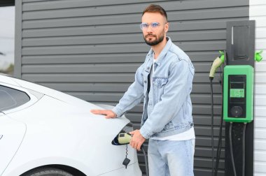 Dışarıdaki otoparkta elektrikli araba için elektrik kablosu. Ve arabayı alışveriş merkezinin yanındaki park yerindeki şarj istasyonuna bağlayacak.