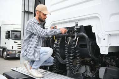 Elektrik kablolarını ticari bir kamyonun römorkuna bağlayan bir sürücü görüntüsü.