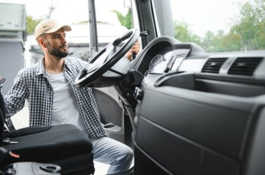 Kamyon şoförü yarı kamyonun taksisine biniyor..