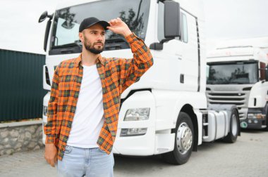 Portrait of young bearded trucker standing by his truck vehicle. Transportation service. Truck driver job. clipart