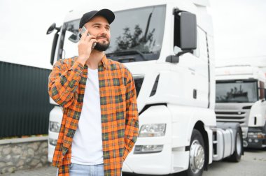 Beyaz kamyonetinin yanında telefonla konuşan bir kamyoncu..