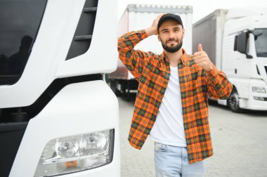 Kamyonun yanında erkek sürücü var. Kamyonun yanında bir kamyon şoförü var. Erkek kamyoncu kamyon sahibi. Ulaşım endüstrisi araçları. Kamyonun önündeki yakışıklı adam.