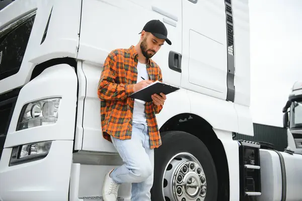 stock image Truck driver checking shipment list while standing on parking lot of distribution warehouse.