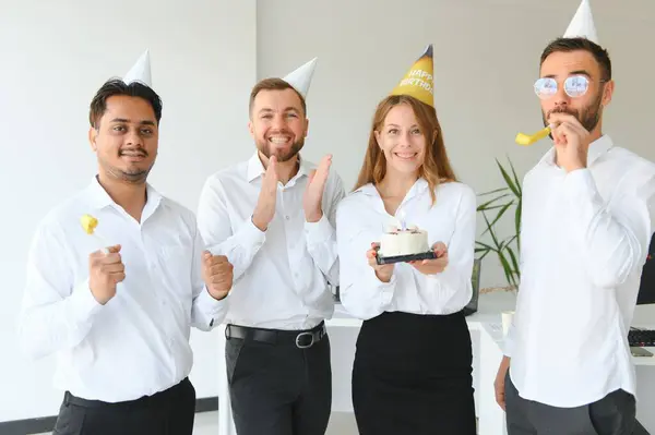 Happy businesswoman holding Birthday cake while making surprise party with her colleagues in the office