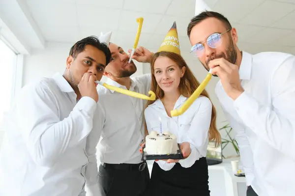 Happy businesswoman holding Birthday cake while making surprise party with her colleagues in the office