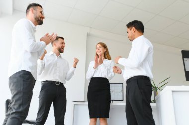 Ofiste yeni bir proje üzerinde çalışırken gülen iş adamları. Çeşitli iş adamlarından oluşan bir grup modern bir çalışma alanında birlikte çalışıyor..
