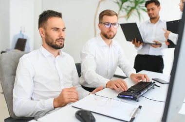 İş adamları. Ofiste zaman geçirirken bilgisayarla veri analiz eden kendinden emin genç iş adamları..