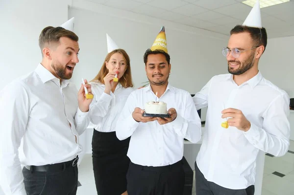 Surprise. Mixed race happy people celebrating a birthday of colleague in the modern office.