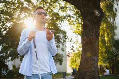 Genç kör adam telefonu kullanıyor ve sesli mesaj gönderiyor..