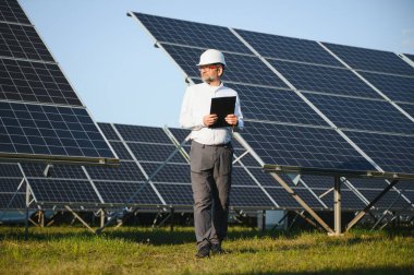 Güneş paneli çiftliğinde çalışan kıdemli mühendis. Yeşil enerji kavramı.