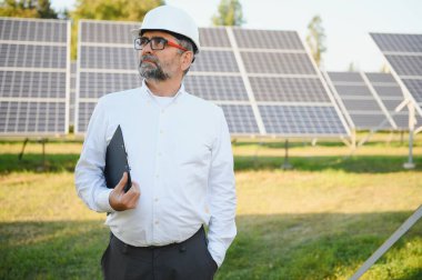 Solar power plant. Man standing near solar panels. Renewable energy.