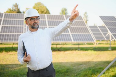 Güneş paneli çiftliğinde çalışan kıdemli mühendis. Yeşil enerji kavramı.