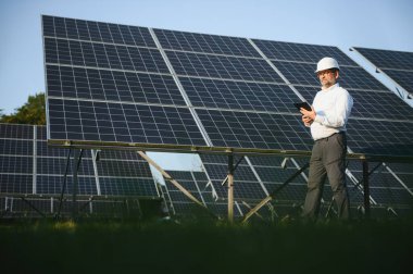 Solar power plant. Man standing near solar panels. Renewable energy.