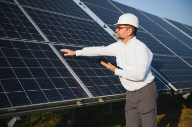 Erkek mühendis çiftlikteki güneş panellerini inceliyor. Temiz enerji