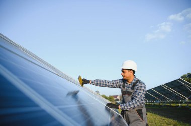 Üniformalı ve aletleri olan Hintli bir işçi güneş paneli çiftliğinde çalışıyor..