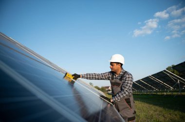 Erkek Arap mühendis güneş panellerindeki direnci kontrol ediyor. İstasyonda çalışan Hintli adam..